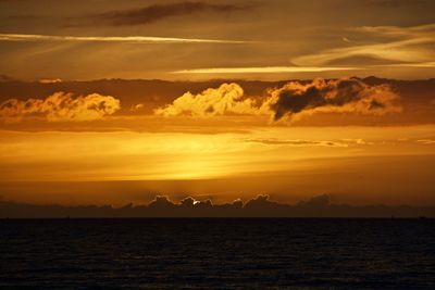 Scenic view of sea against cloudy sky during sunset