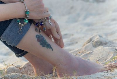 Low section of woman sitting on beach