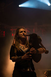 Young woman with arms outstretched standing at night
