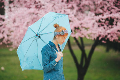 Portrait of a woman with blue umbrella in front of the spring blossom