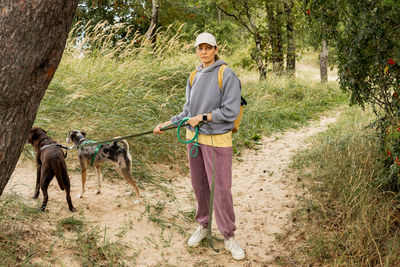 Rear view of man with dog standing in forest