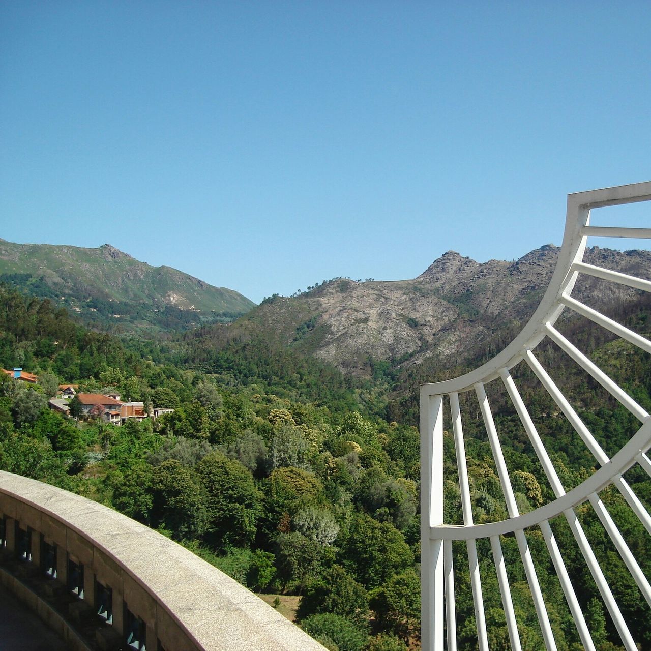 clear sky, mountain, built structure, architecture, copy space, blue, railing, mountain range, high angle view, tree, building exterior, landscape, scenics, nature, tranquility, day, tranquil scene, outdoors, travel destinations, no people