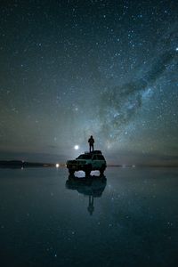 Silhouette man in sea against sky at night