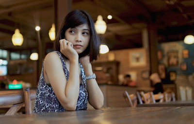 Thoughtful woman sitting at table in restaurant