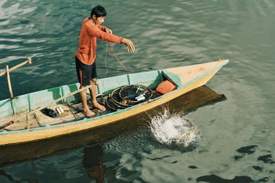 High angle view of man fishing on boat in lake