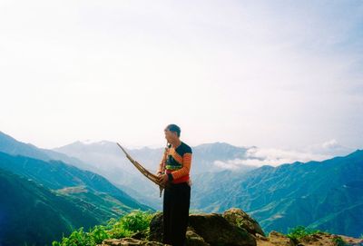 Side view of man standing on mountain against sky