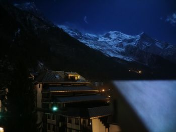 Illuminated buildings against sky at night during winter