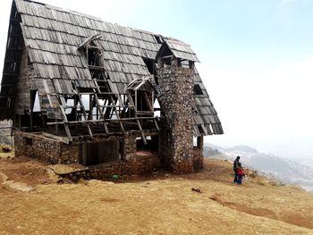 Father and daughter by old abandoned building against sky