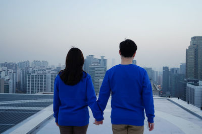 Rear view of man and woman standing against clear sky