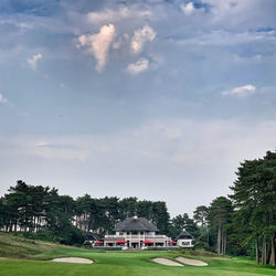 Road amidst trees and buildings against sky