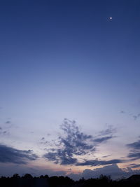 Low angle view of silhouette trees against blue sky