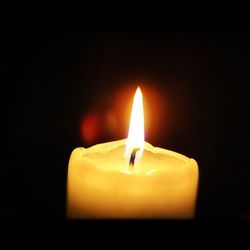 Close-up of lit candle in dark room