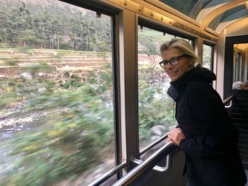 Side view of man standing by train window