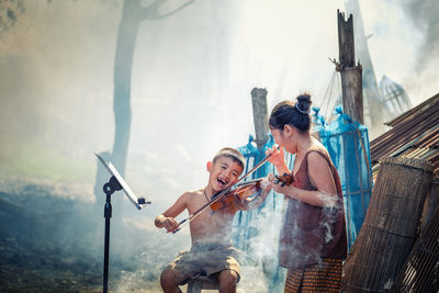 Playful siblings playing violin outdoors