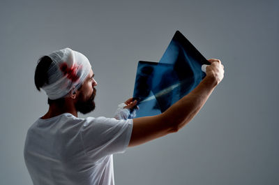 Portrait of young man holding hat against white background