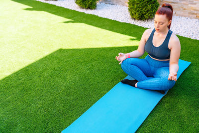 Portrait of young woman exercising on field