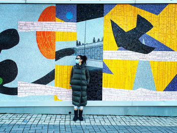 Full length of woman standing against graffiti wall