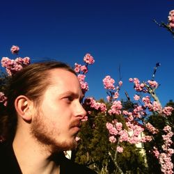 Thoughtful man standing against pink flowers