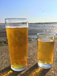 Close-up of beer glasses on retaining wall by beach