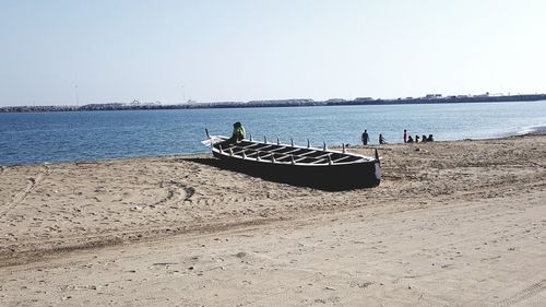 People on beach against clear sky