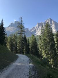 Road amidst trees and mountains against sky