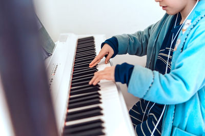 Midsection of boy playing piano