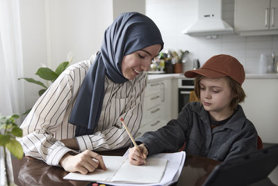 Mother helping son with homework at home