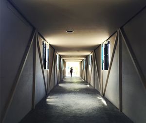 Rear view of woman walking in illuminated tunnel