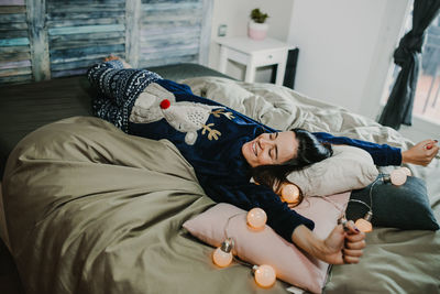 High angle view of smiling woman lying on bed at home