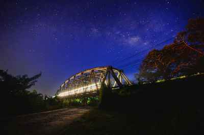 Blurred motion of illuminated train on bridge against star field at night