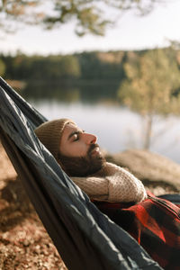 Man with beard resting with eyes closed in hammock