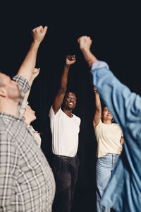 Multiracial male and female artists practicing with hands raised in class