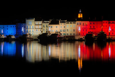 Reflection of illuminated buildings on river in city at night