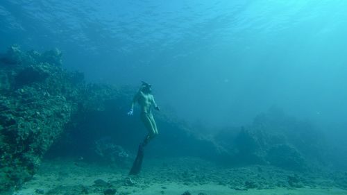 Long haired man freediving 40 feet below the seas surface