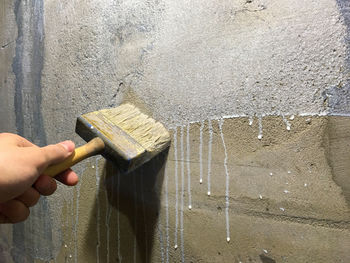 Close-up of woman hand holding wood against wall