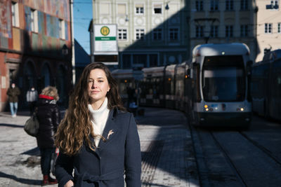 Portrait of young woman with umbrella in city