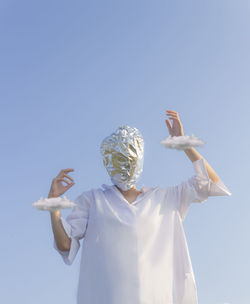 Rear view of woman with arms raised against clear sky