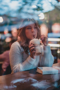 Young woman drinking water from coffee in restaurant