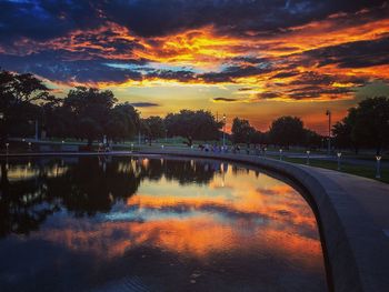 Reflection of trees against sky during sunset