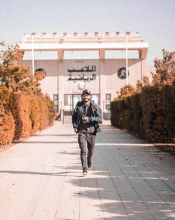 Full length portrait of man walking on footpath in city