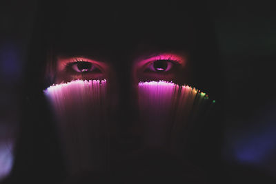 Close-up portrait of young woman holding illuminated fiber optic