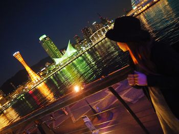 Midsection of woman standing in illuminated city against clear sky at night