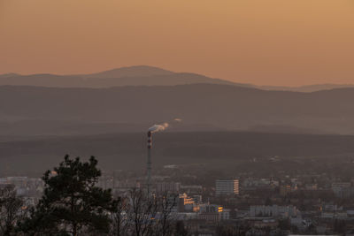 Scenic view of mountains and buildings against sky during sunset