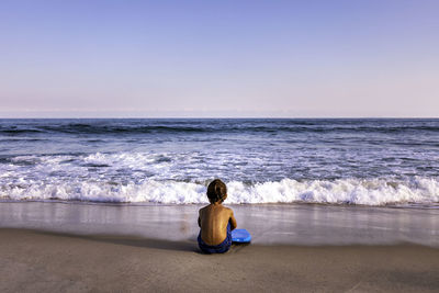 Rear view of woman sitting on beach