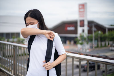 Woman standing by railing in city