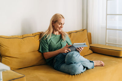 Young woman using laptop while sitting on sofa at home