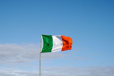 Low angle view of flag waving against blue sky during sunny day