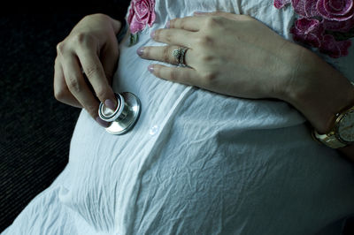 Midsection of pregnant woman holding stethoscope