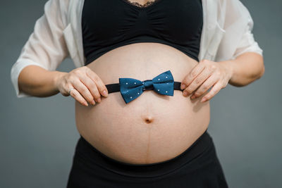 Midsection of woman wearing mask against gray background