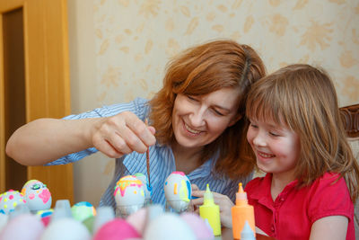 Mother and daughter making easter eggs on table